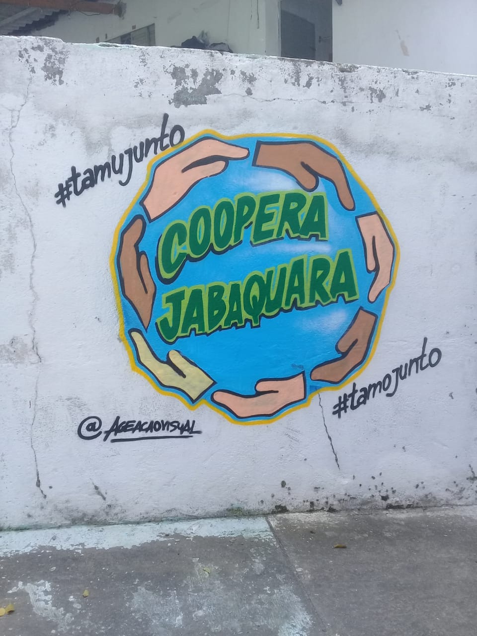 Grafite do logotipo do Programa Coopera - Um circulo envolto por mão de diversas raças, o circulo está em azul e dentro está escrito coopera Jabaquara